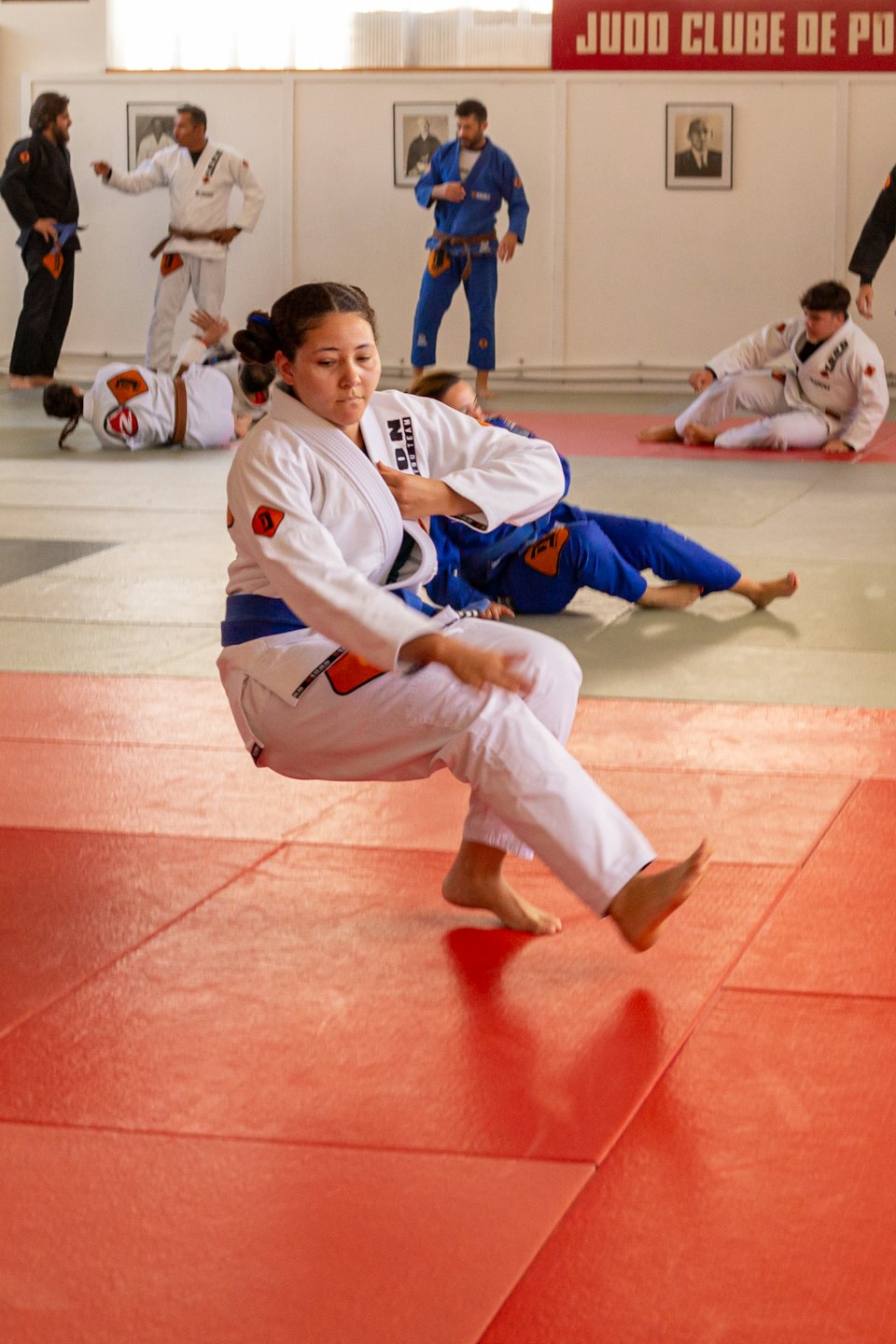 Donna in gi bianca pratica arti marziali su tappeti rossi.